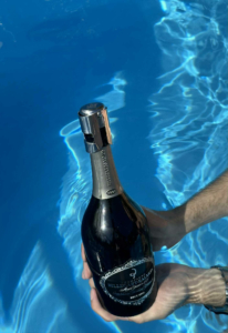Öppnad vinflaska med elegant vinpropp i rostfritt stål, i en pool utomhus